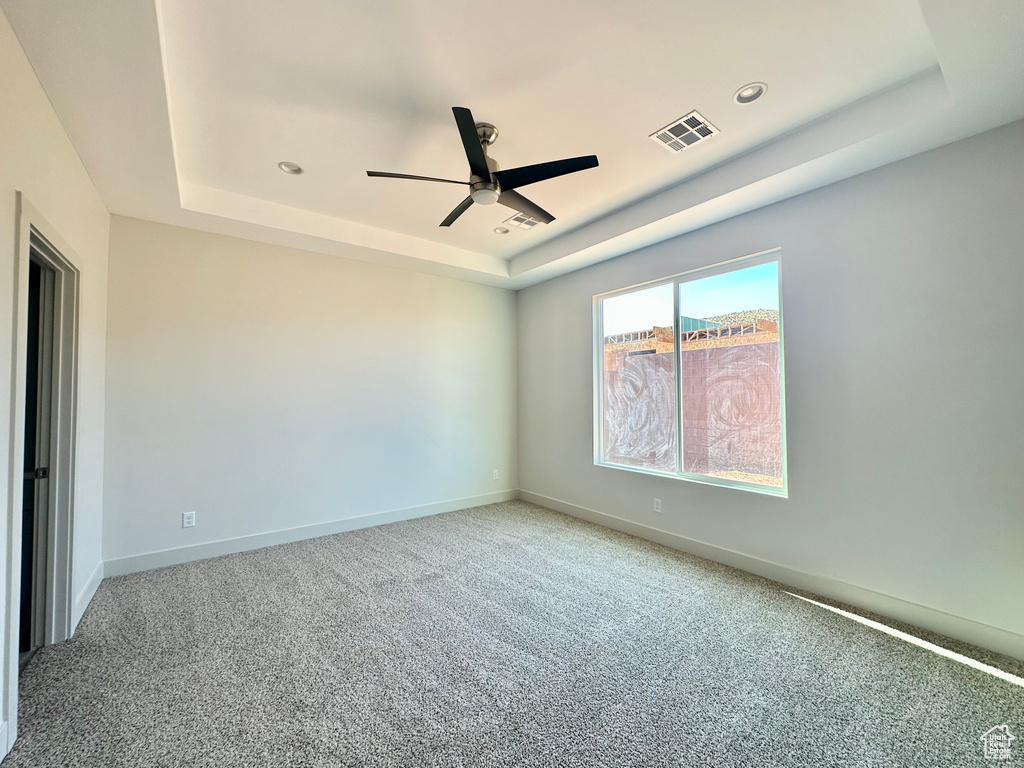 Carpeted empty room with a tray ceiling and ceiling fan