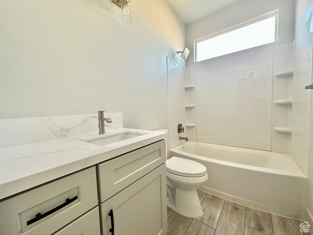 Full bathroom with shower / bathtub combination, hardwood / wood-style flooring, vanity, and toilet