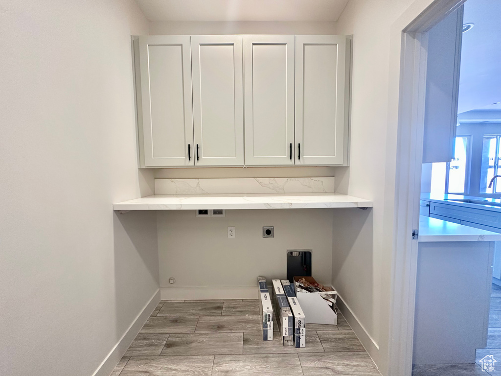 Laundry area with cabinets, light wood-type flooring, sink, and electric dryer hookup