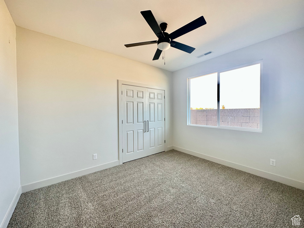 Unfurnished bedroom featuring ceiling fan, carpet floors, and a closet