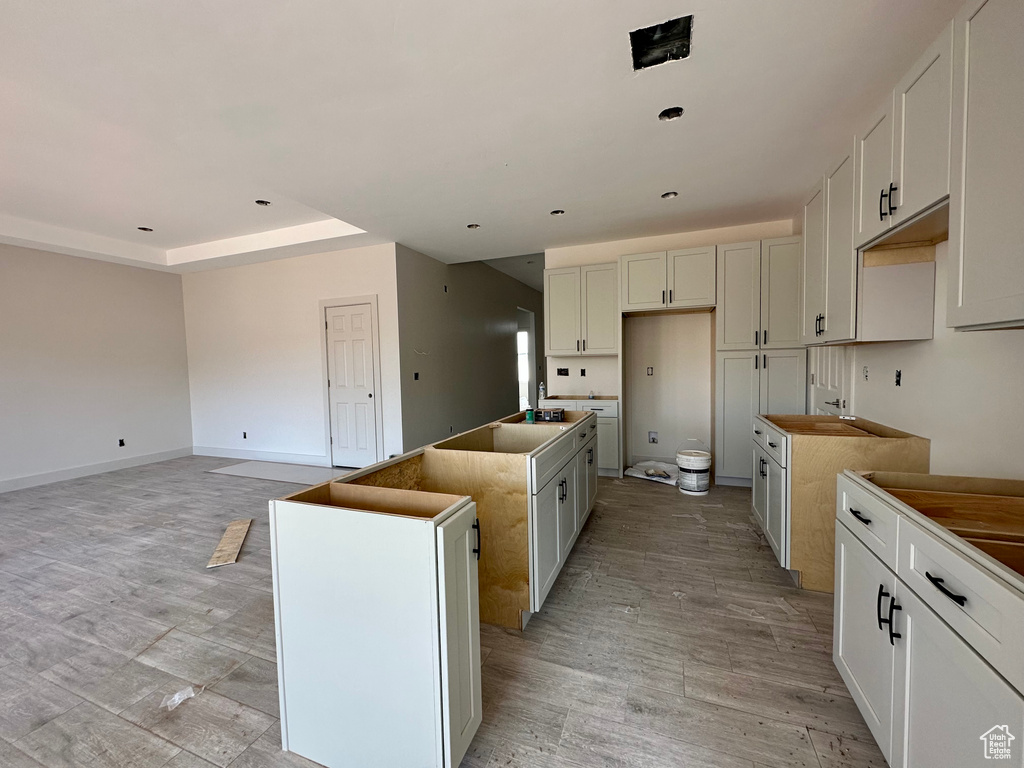 Kitchen with light wood-type flooring, white cabinets, and a center island