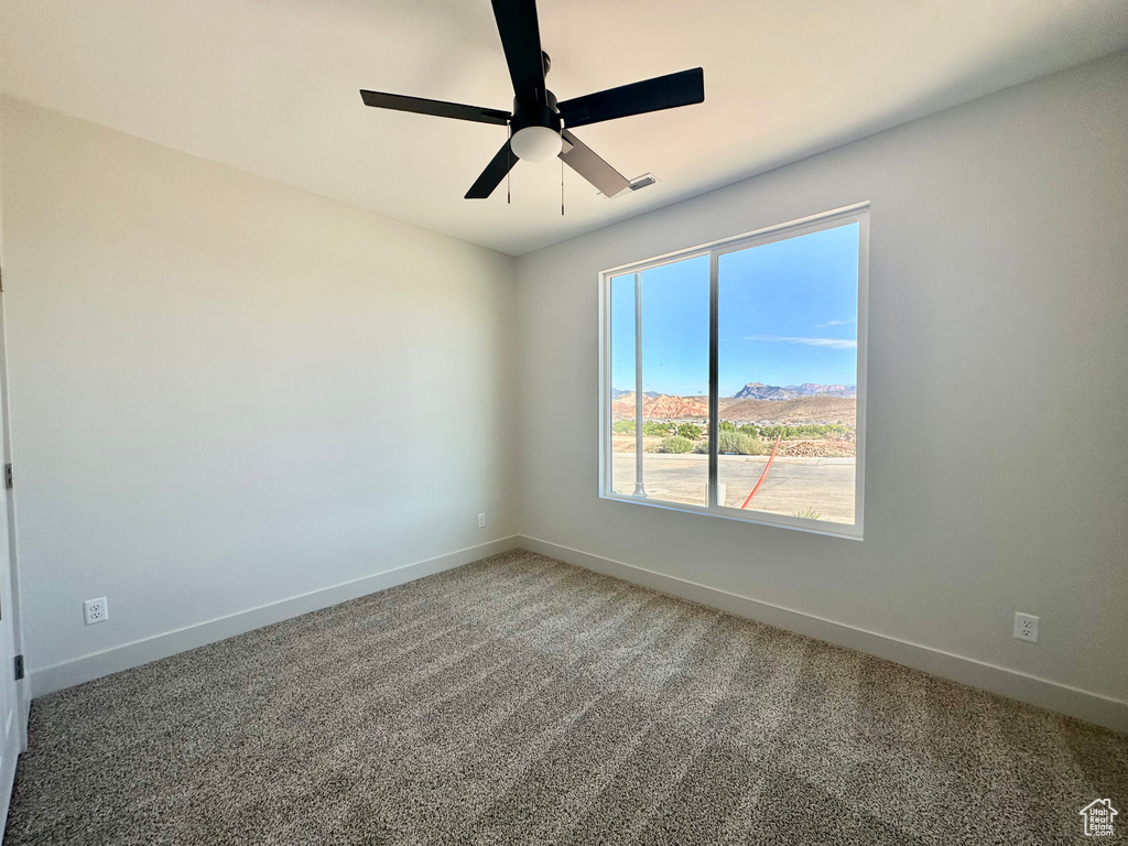 Spare room featuring carpet floors, a mountain view, and ceiling fan