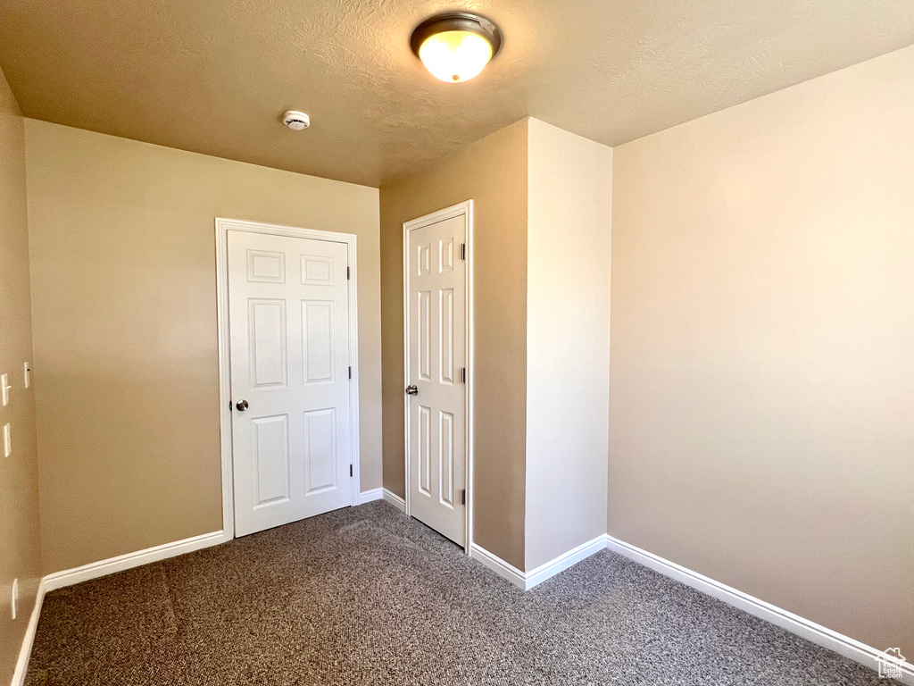 Unfurnished bedroom with carpet and a textured ceiling