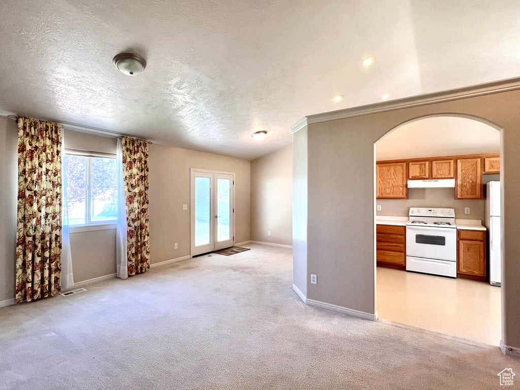 Kitchen featuring light carpet, vaulted ceiling, a textured ceiling, and white electric stove