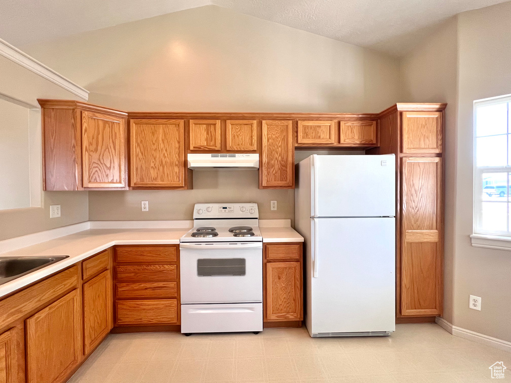 Kitchen featuring high vaulted ceiling, white appliances, and sink