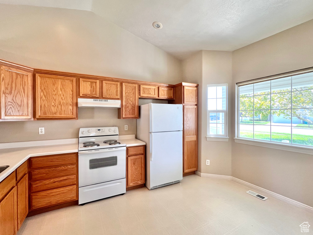 Kitchen featuring white appliances and high vaulted ceiling