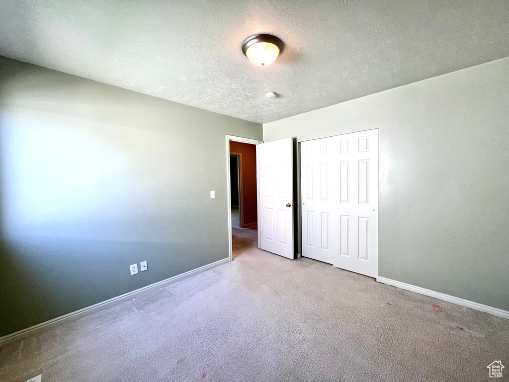 Empty room with light carpet and a textured ceiling