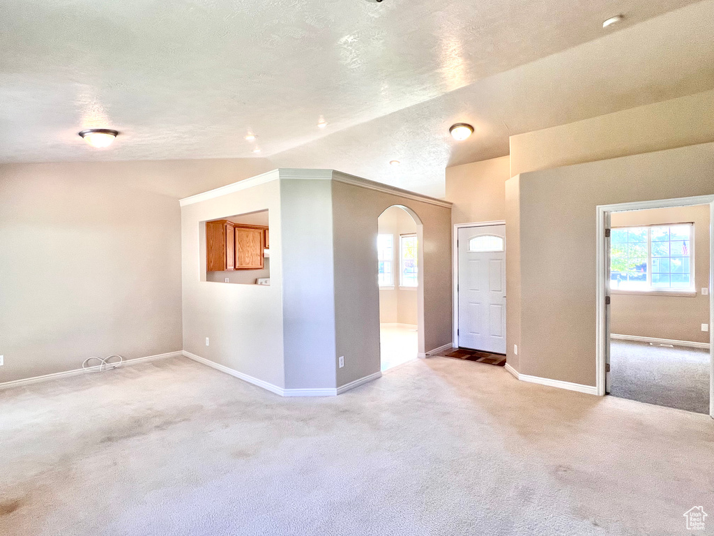 Spare room featuring vaulted ceiling, a textured ceiling, and carpet