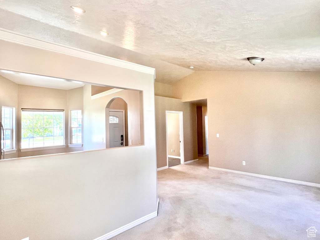 Carpeted empty room featuring vaulted ceiling and a textured ceiling