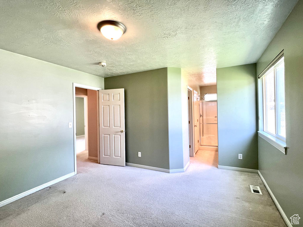 Unfurnished bedroom featuring a textured ceiling and light colored carpet