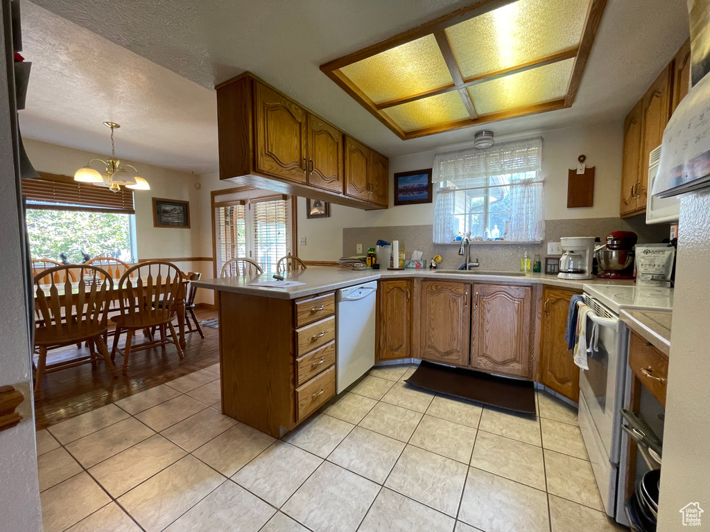 Kitchen with a textured ceiling, an inviting chandelier, white appliances, pendant lighting, and light tile patterned floors