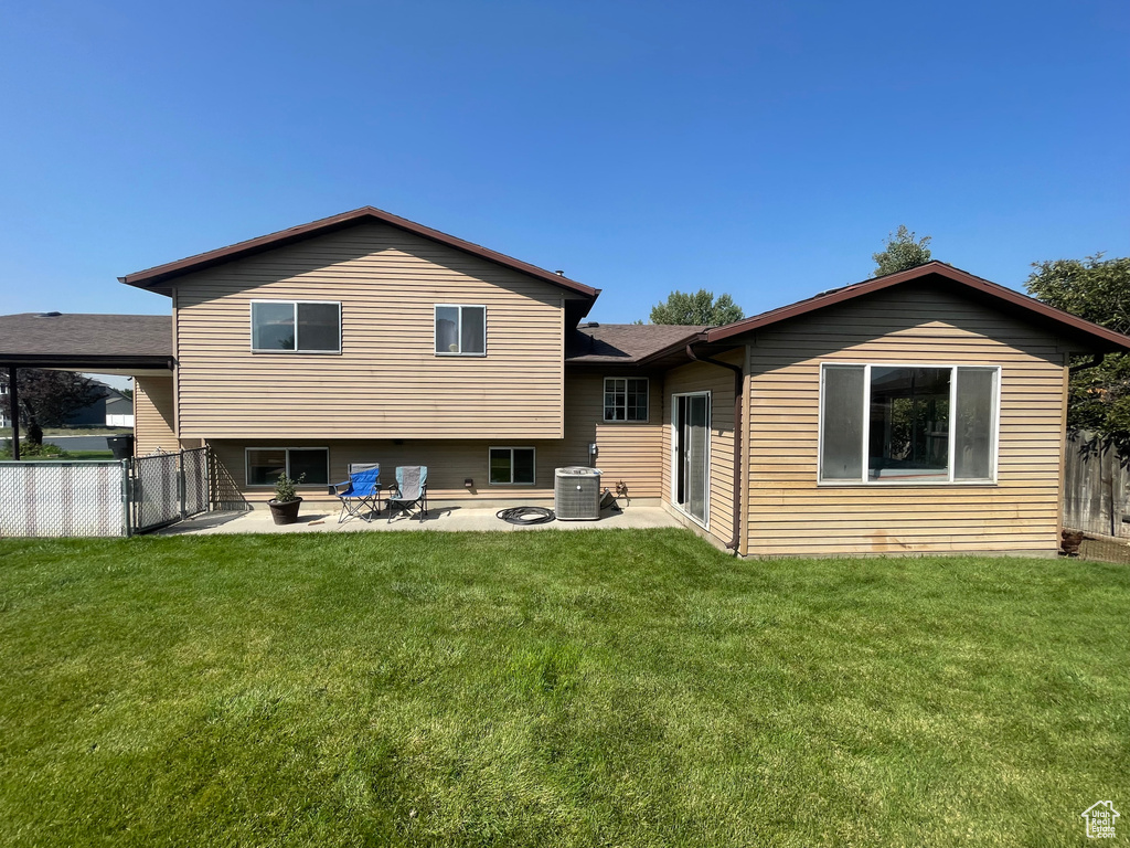 Back of house featuring a lawn, a patio, and central AC