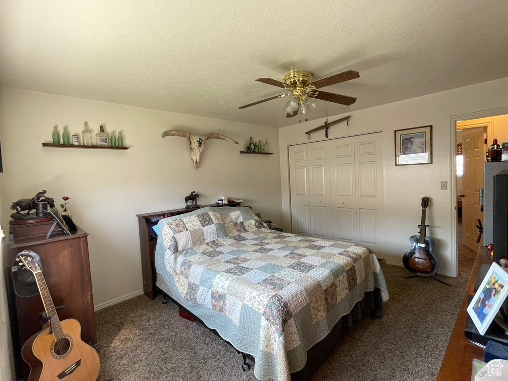 Carpeted bedroom with a textured ceiling, ceiling fan, and a closet