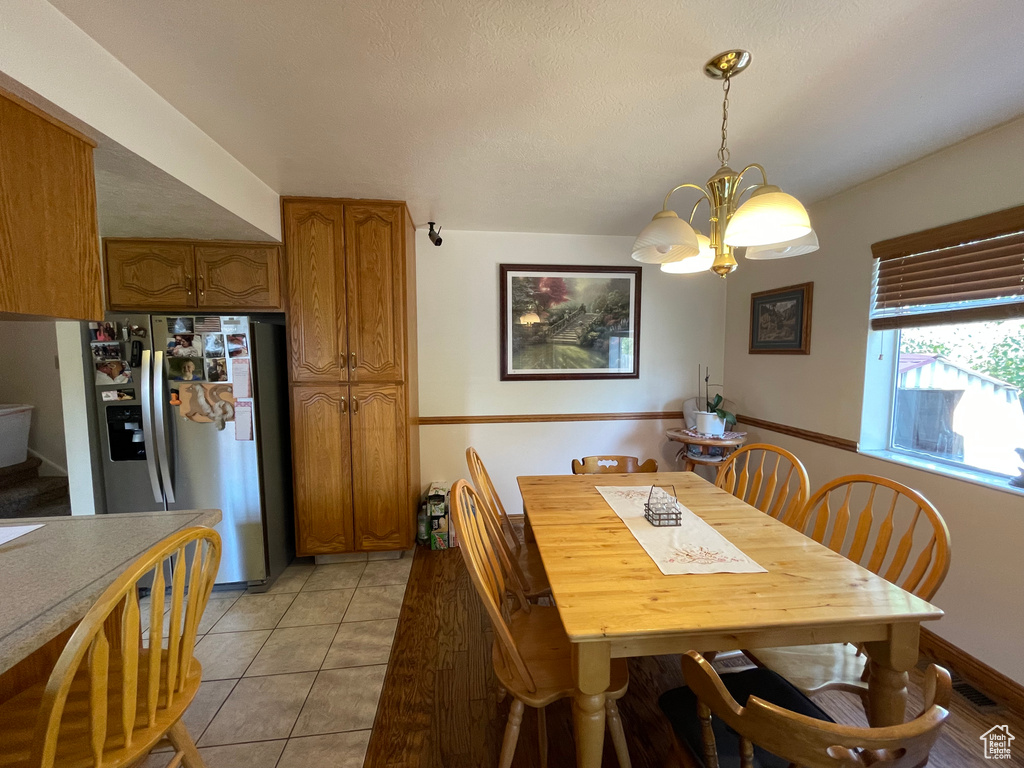 Dining area featuring a notable chandelier, a textured ceiling, and light tile patterned flooring