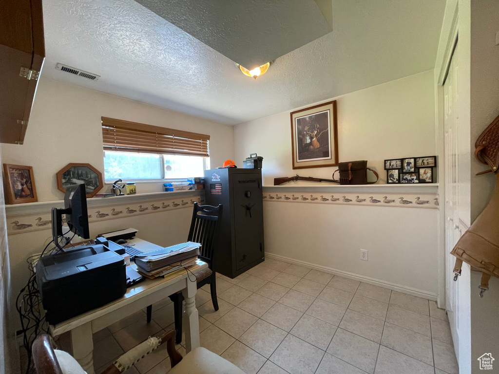 Interior space featuring light tile patterned flooring and a textured ceiling