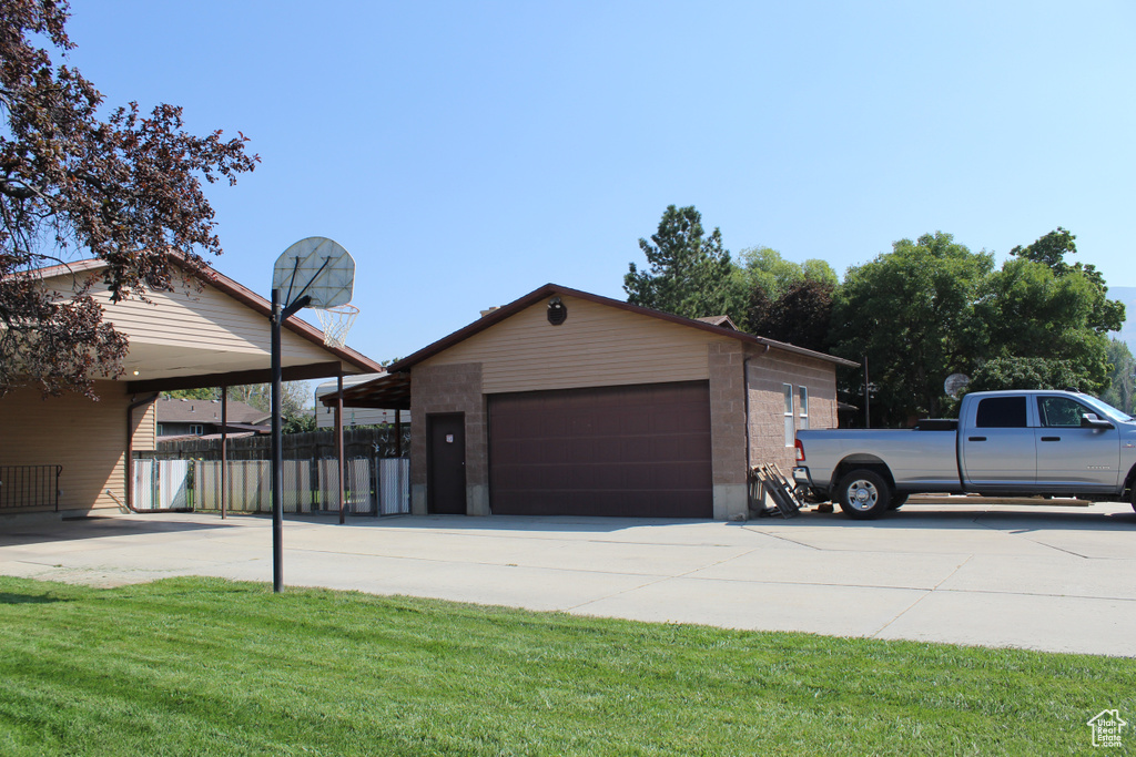 Exterior space with a front lawn, a garage, a carport, and an outdoor structure