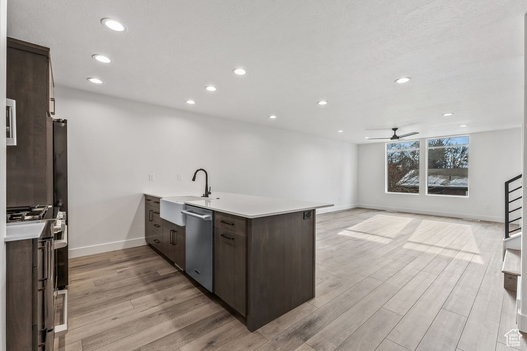 Kitchen with light wood-type flooring, appliances with stainless steel finishes, sink, kitchen peninsula, and ceiling fan