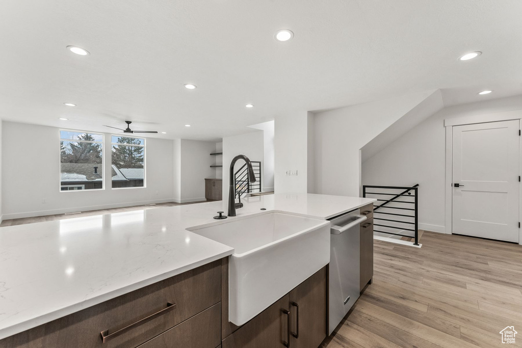 Kitchen with dishwasher, sink, ceiling fan, dark brown cabinetry, and light wood-type flooring