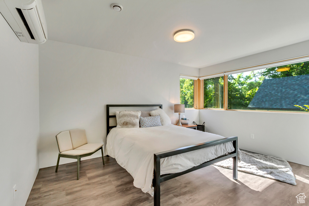 Bedroom featuring a wall unit AC and wood-type flooring