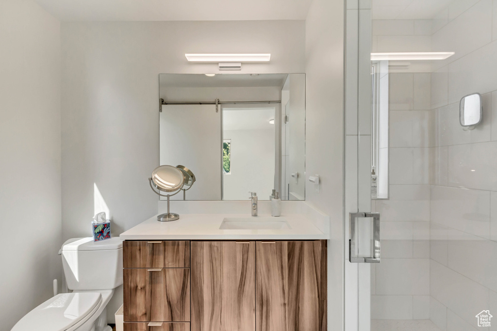 Bathroom featuring toilet, an enclosed shower, and vanity