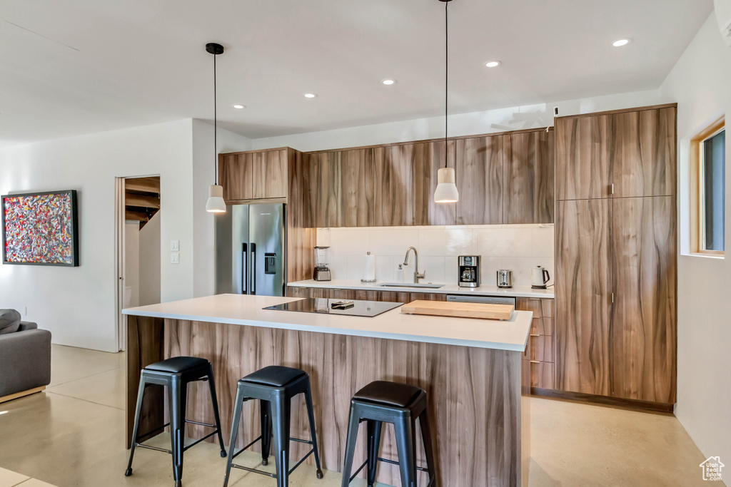 Kitchen featuring pendant lighting, a center island, a breakfast bar area, and stainless steel refrigerator with ice dispenser