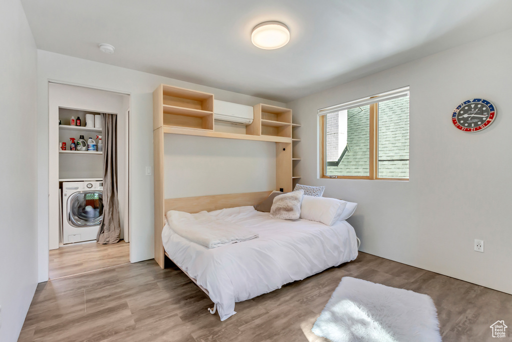 Bedroom featuring light hardwood / wood-style flooring, washer / dryer, and an AC wall unit