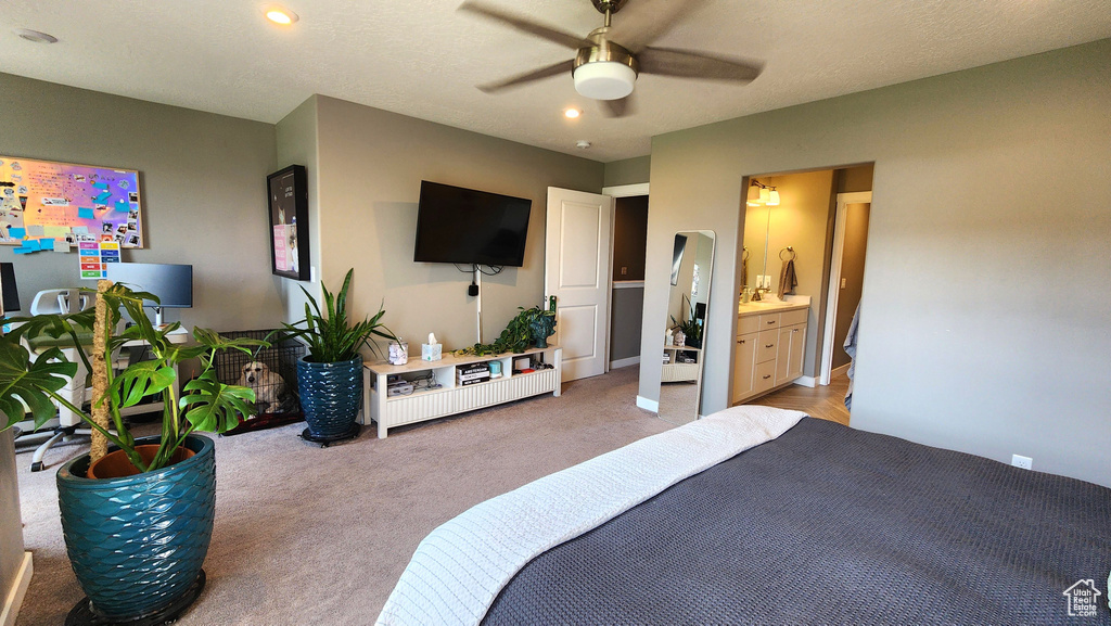 Bedroom with ensuite bath, light colored carpet, ceiling fan, and a textured ceiling