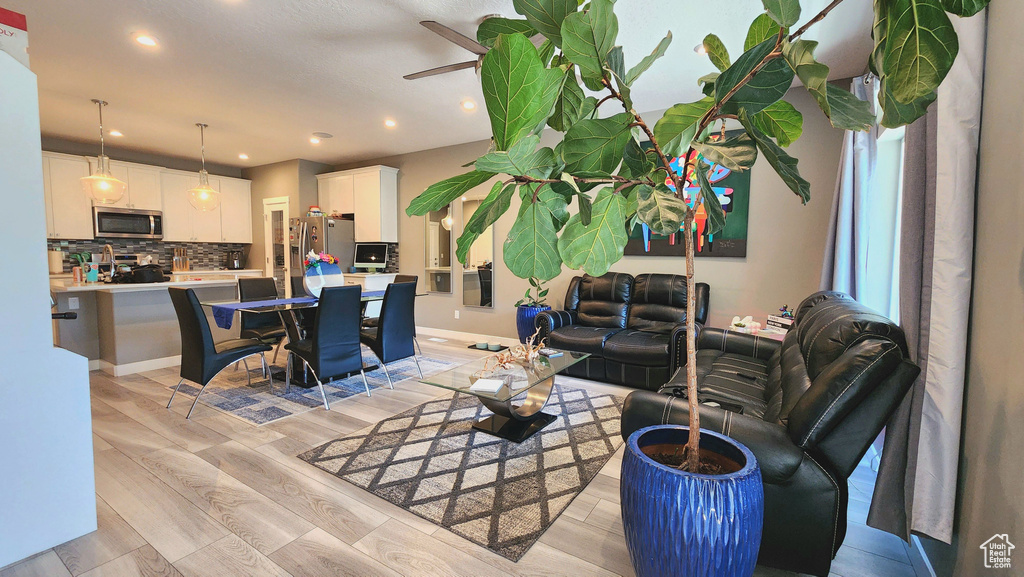 Living room with ceiling fan and light hardwood / wood-style flooring