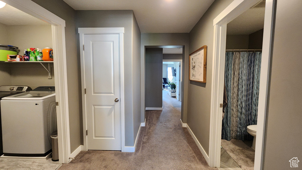 Clothes washing area featuring independent washer and dryer and light colored carpet