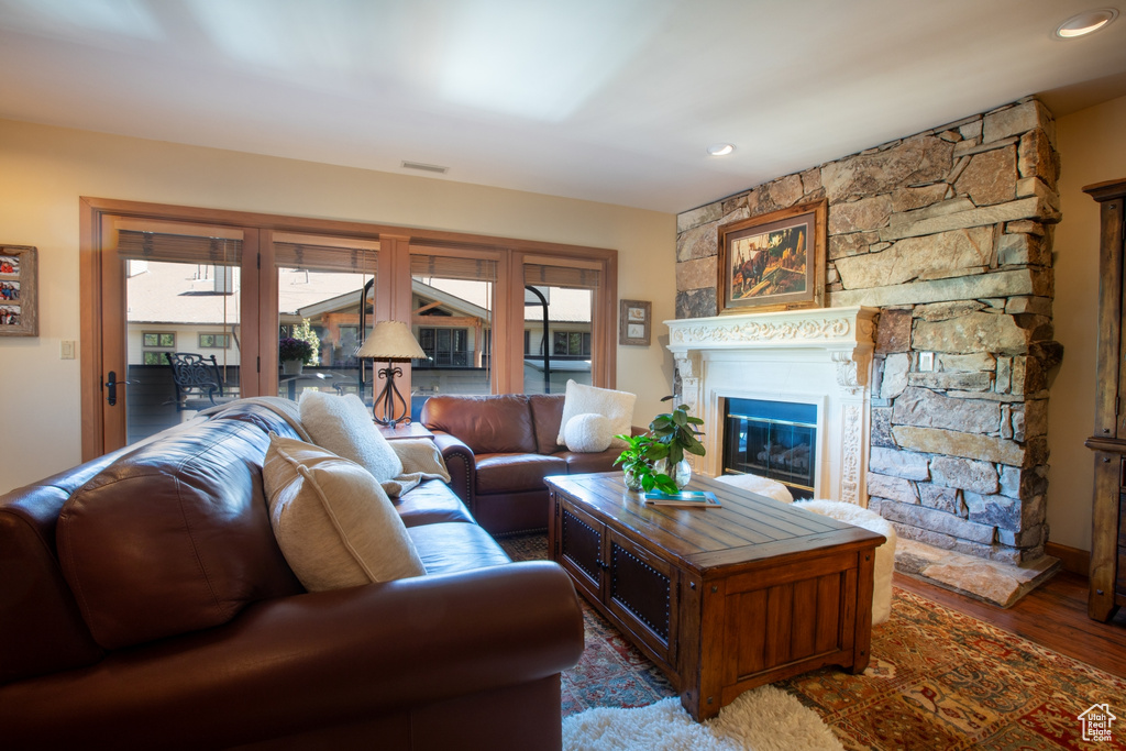 Living room with dark hardwood / wood-style flooring and a stone fireplace