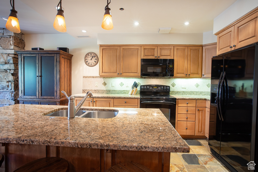 Kitchen featuring sink, black appliances, a kitchen breakfast bar, pendant lighting, and decorative backsplash