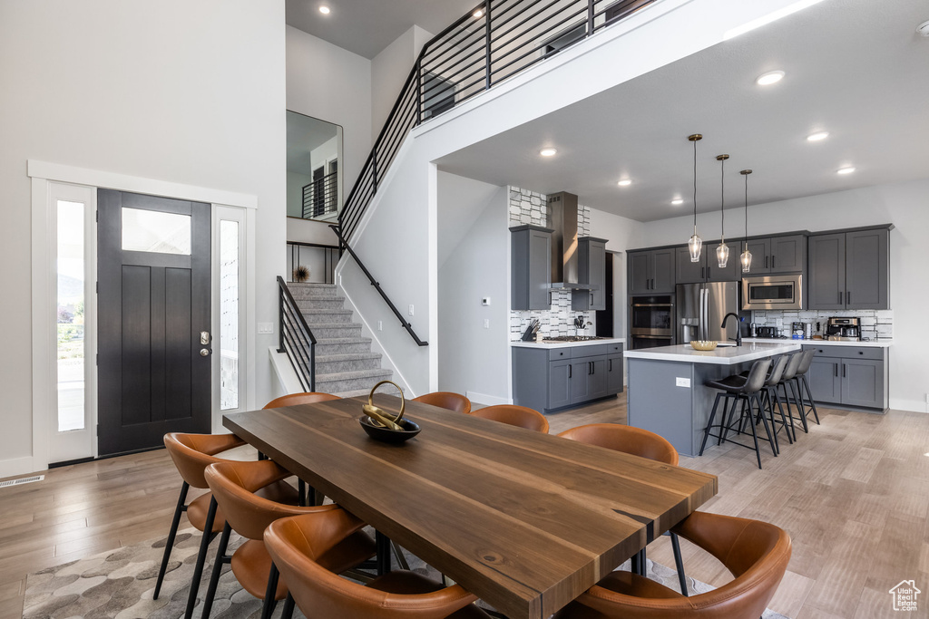 Dining area featuring light wood-type flooring and a towering ceiling