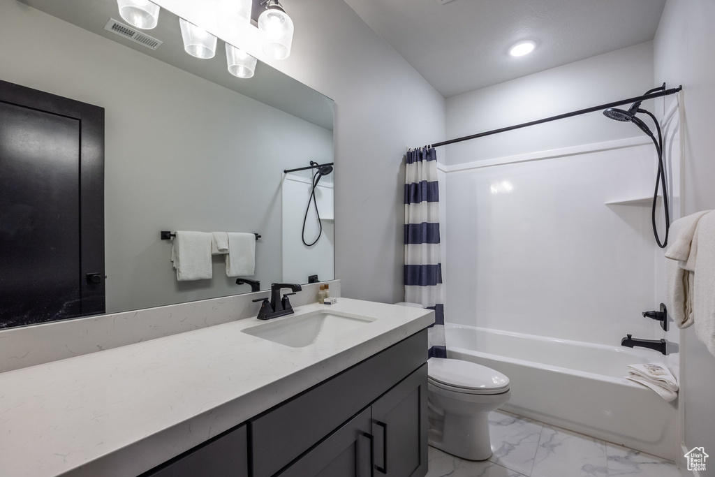 Full bathroom featuring toilet, shower / tub combo with curtain, and vanity