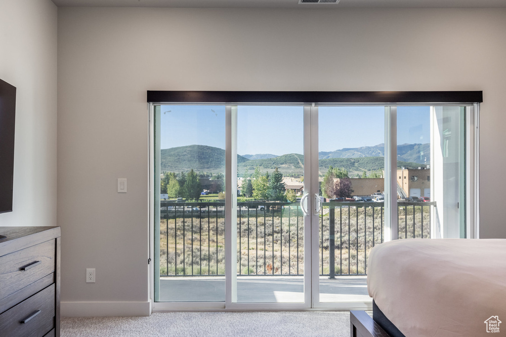 Carpeted bedroom with access to exterior, a mountain view, and multiple windows