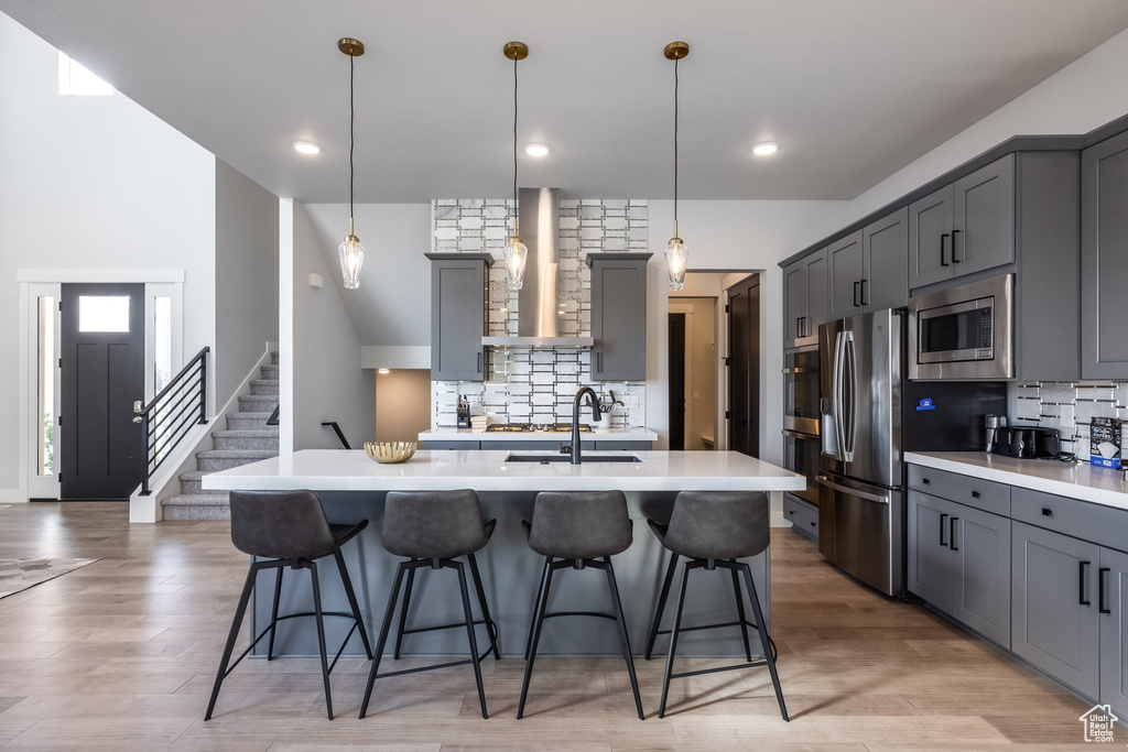 Kitchen featuring gray cabinets, appliances with stainless steel finishes, and wall chimney exhaust hood