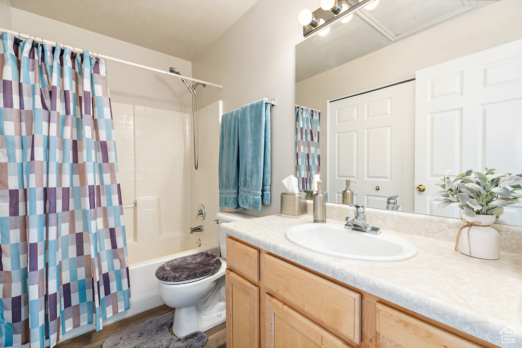 Full bathroom with vanity, toilet, wood-type flooring, and shower / bath combo