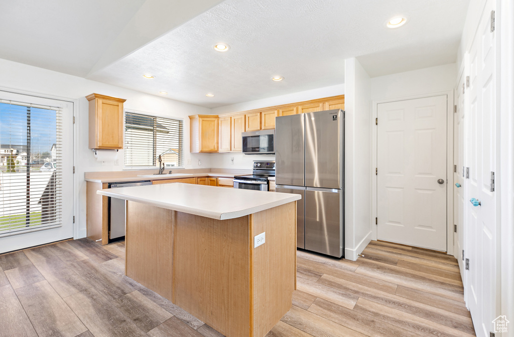 Kitchen featuring light brown cabinetry, light hardwood / wood-style flooring, appliances with stainless steel finishes, sink, and a kitchen island