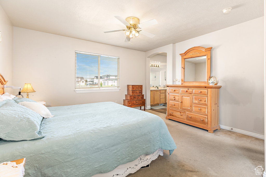 Carpeted bedroom featuring ceiling fan and connected bathroom