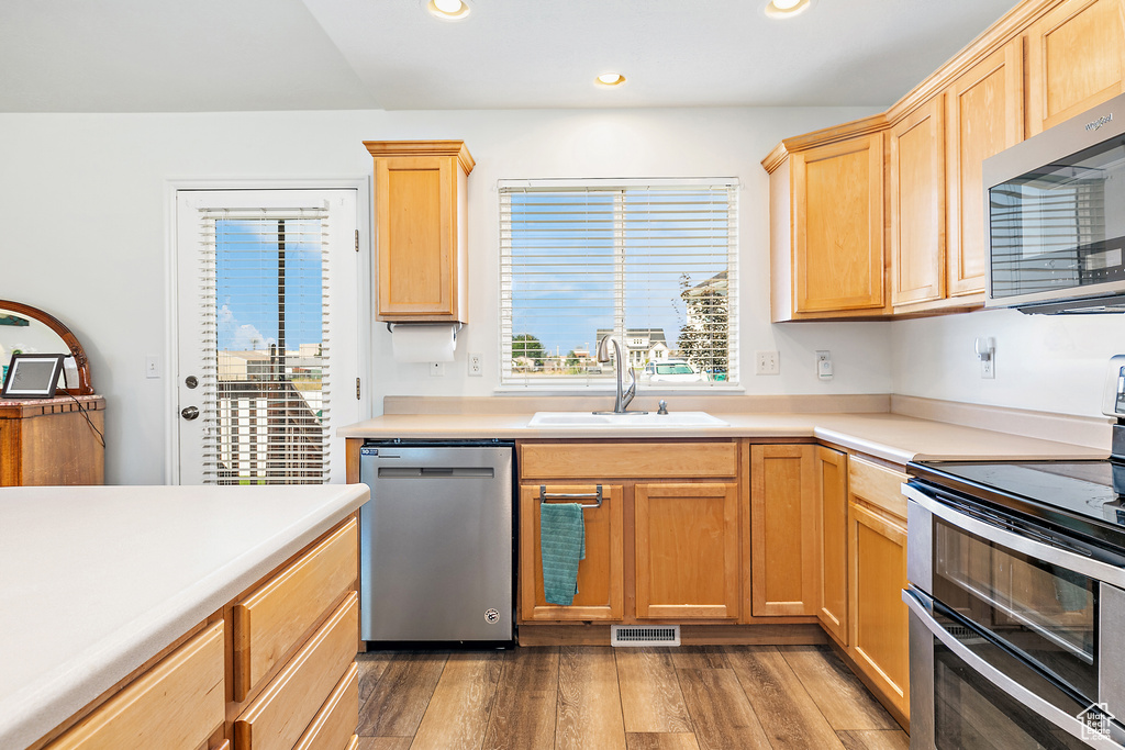 Kitchen featuring appliances with stainless steel finishes, wood-type flooring, sink, and light brown cabinets