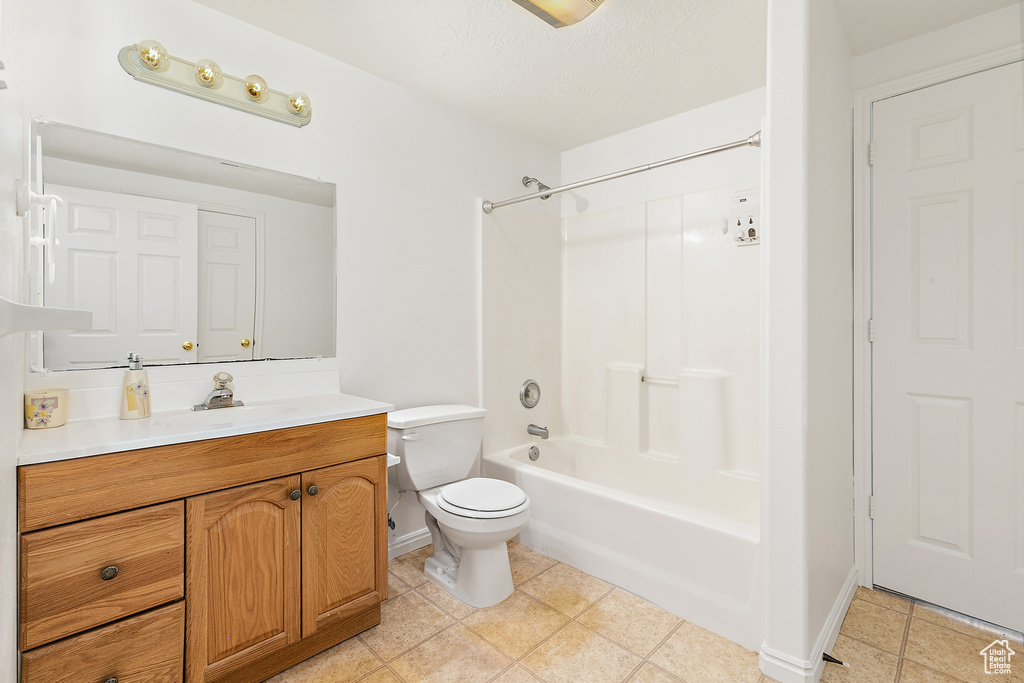 Full bathroom with a textured ceiling, vanity, tile patterned flooring, toilet, and tub / shower combination