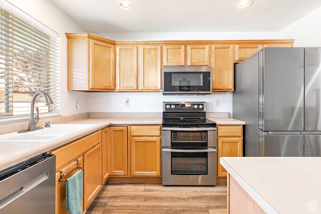 Kitchen featuring light brown cabinets, light hardwood / wood-style flooring, stainless steel appliances, and sink