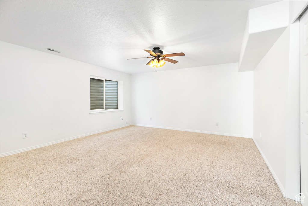 Spare room with ceiling fan, light colored carpet, and a textured ceiling