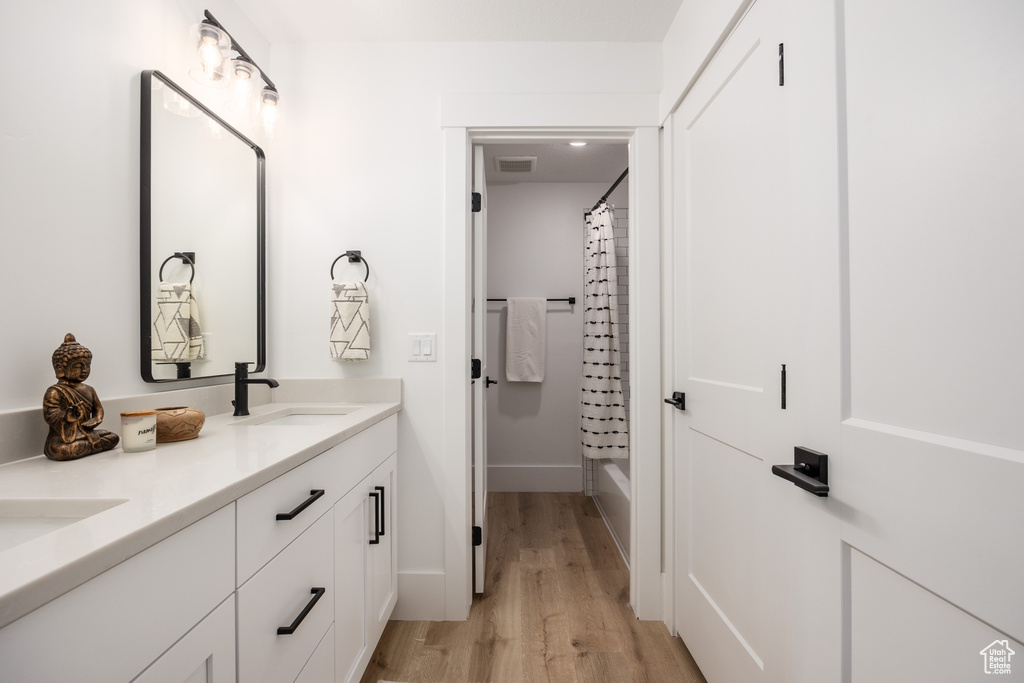 Bathroom with shower / bath combination with curtain, hardwood / wood-style flooring, and vanity