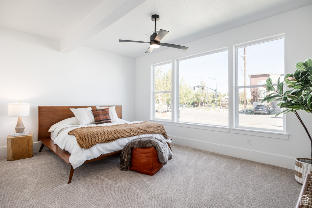 Carpeted bedroom with ceiling fan and beamed ceiling