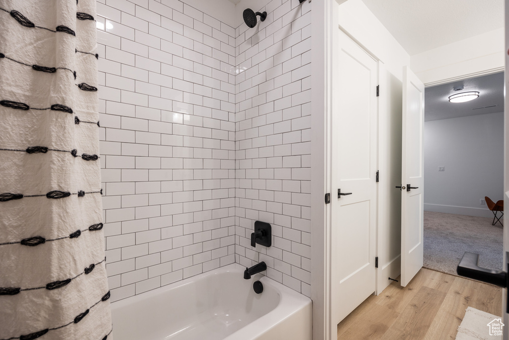 Bathroom with tiled shower / bath combo and wood-type flooring