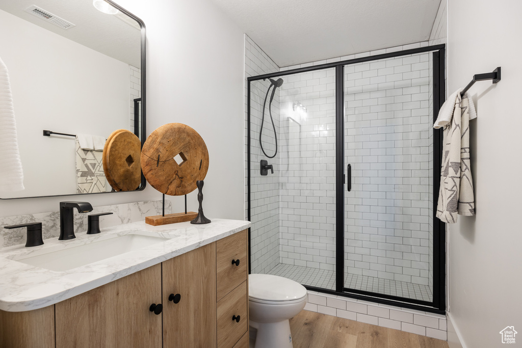 Bathroom featuring vanity, toilet, hardwood / wood-style floors, and an enclosed shower