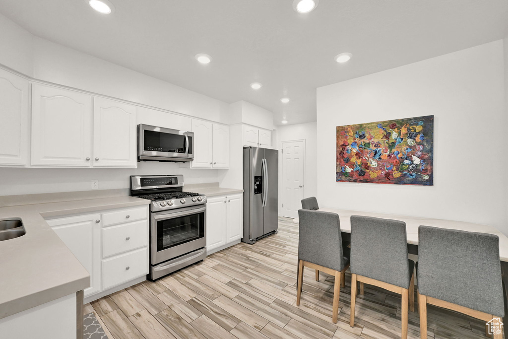 Kitchen featuring appliances with stainless steel finishes, light hardwood / wood-style floors, and white cabinetry