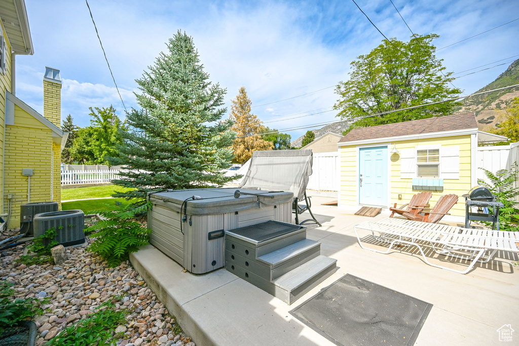 View of patio / terrace with a hot tub, cooling unit, and a grill