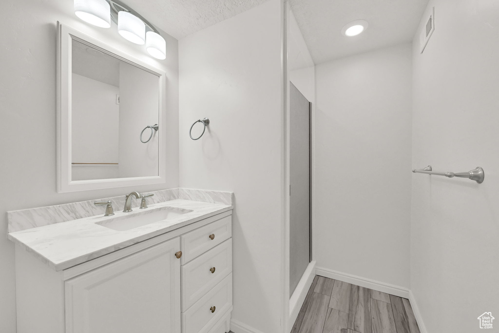 Bathroom featuring a textured ceiling, vanity, and wood-type flooring