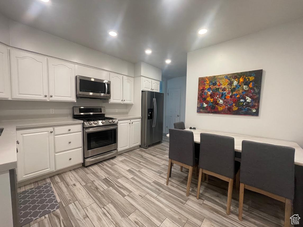 Kitchen featuring light wood-type flooring, appliances with stainless steel finishes, and white cabinets